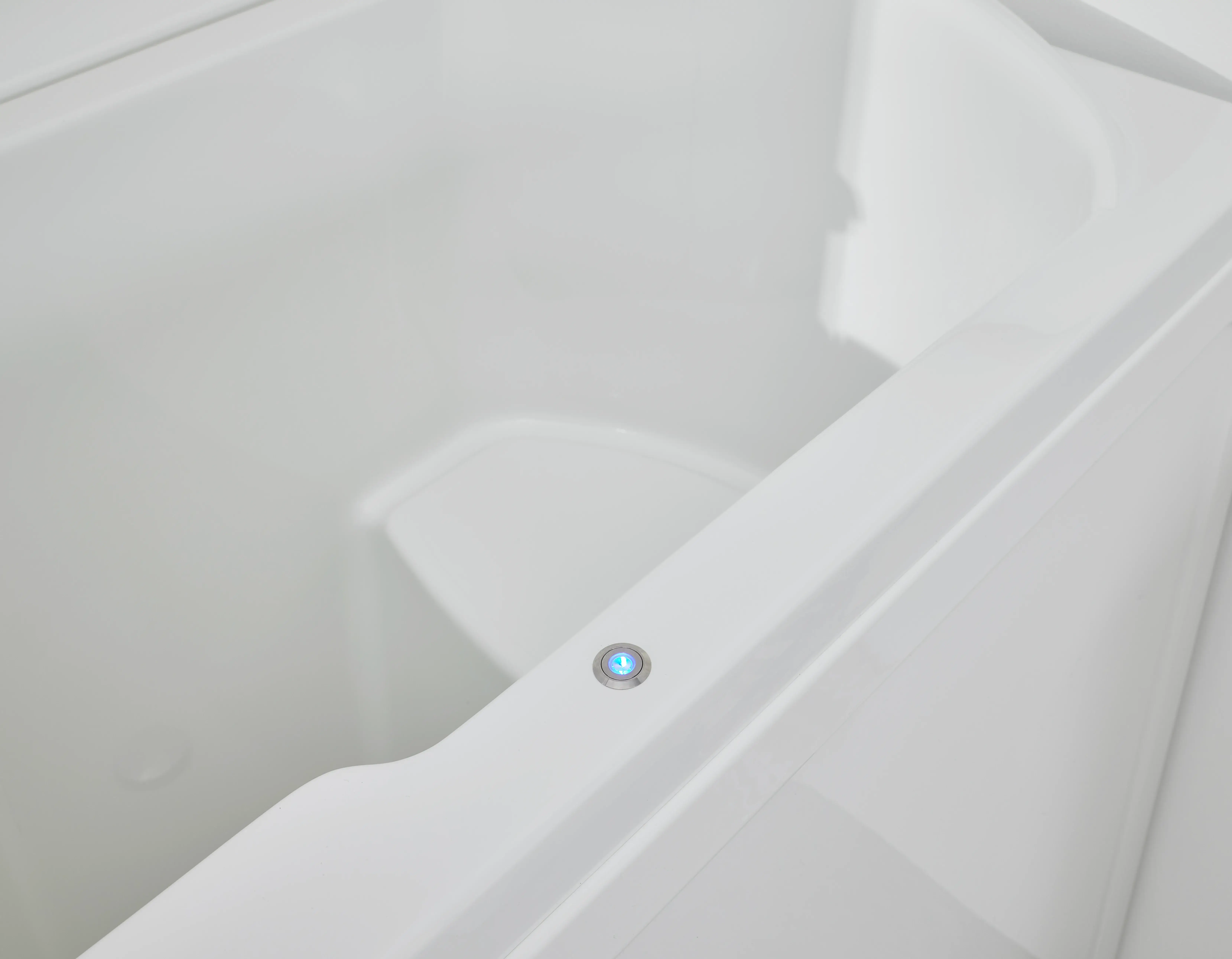 A white bathtub with a blue light on the side of it.